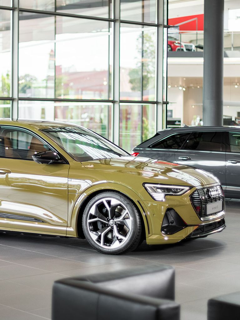 Side view of the Audi e-tron S in yellow in an Audi Centre