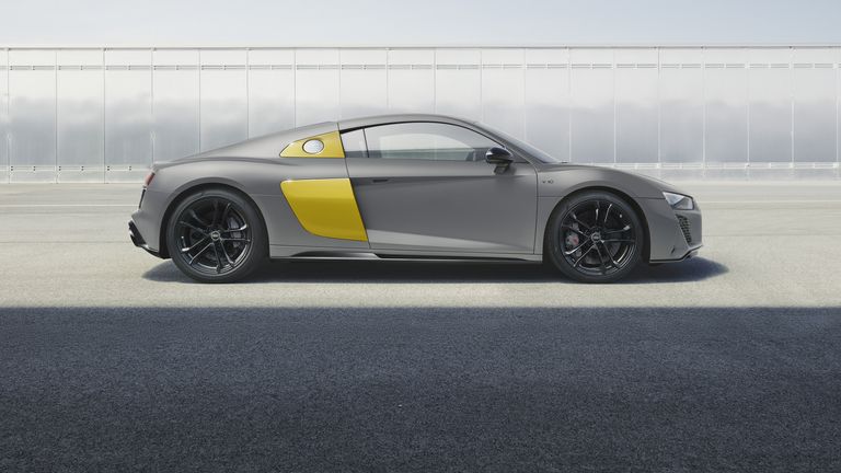 Seitliche Ansicht des R8 Coupé V10 performance quattro RWD mit gelben Sideblades vor einer Wand aus Metallplatten